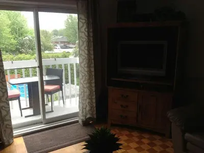 a living room with a television and a balcony at Maison Parc Delormier in Trois-Rivières