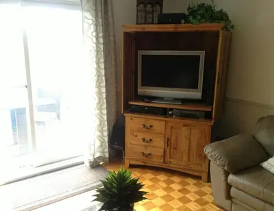 a living room with a television on a wooden cabinet at Maison Parc Delormier in Trois-Rivières