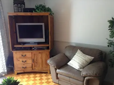 a living room with a couch and a television on a cabinet at Maison Parc Delormier in Trois-Rivières
