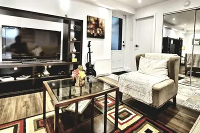 a living room with a television and a chair and a glass table at Cosy apartment at Bossuet road in Montréal