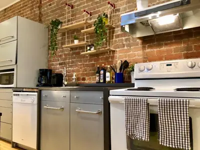 a kitchen with white appliances and a brick wall at Le Duplex VIP in Montréal