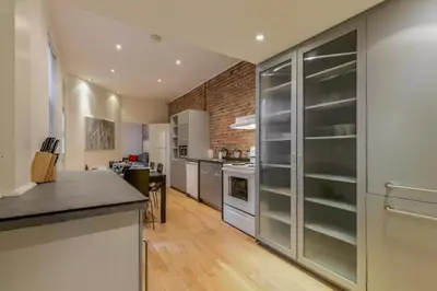 a kitchen with white appliances and a brick wall at Le Duplex VIP in Montréal