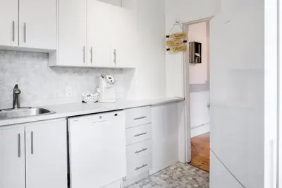 a white kitchen with white cabinets and a sink at MtlVacationRentals - Appartements Plateau-Mont-Royal in Montréal