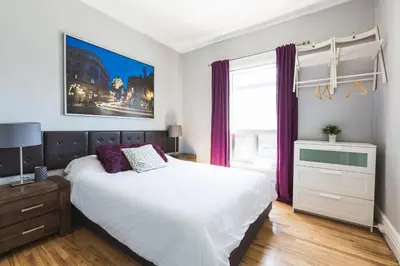 a bedroom with a white bed with purple curtains at MtlVacationRentals - Appartements Plateau-Mont-Royal in Montréal