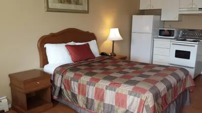 a small bedroom with a bed and a refrigerator at Motel Iberville in Saint-Jean-sur-Richelieu