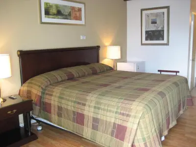 a bedroom with a large bed with a plaid blanket at Motel Iberville in Saint-Jean-sur-Richelieu