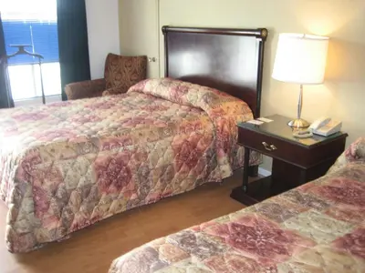 a hotel room with two beds and a table with a lamp at Motel Iberville in Saint-Jean-sur-Richelieu