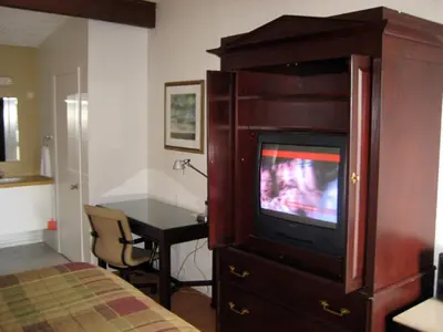 a bedroom with a tv in a wooden entertainment center at Motel Iberville in Saint-Jean-sur-Richelieu