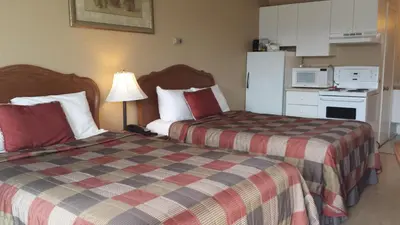 a hotel room with two beds and a refrigerator at Motel Iberville in Saint-Jean-sur-Richelieu