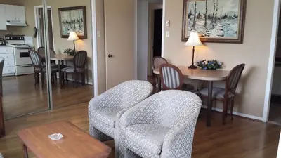 a living room with chairs and a table and a kitchen at Motel Iberville in Saint-Jean-sur-Richelieu