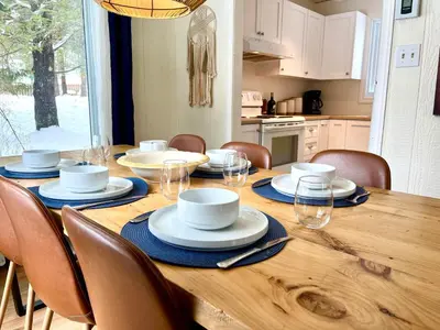 a wooden table with chairs and plates and cups on it at Le Jackrabbit Orford Domaine Cheribourg in Orford