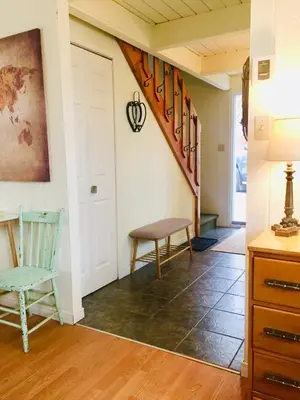 a hallway with a door and a chair and a stairway at Le Jackrabbit Orford Domaine Cheribourg in Orford