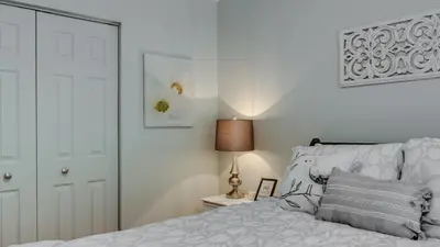 a white bedroom with a bed and a lamp at Condo Entre Ville et Nature 2 in Magog-Orford