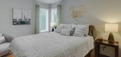 a white bedroom with a bed and a lamp at Condo Entre Ville et Nature 2 in Magog-Orford