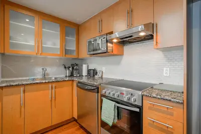 a kitchen with wooden cabinets and stainless steel appliances at Le Mille Neuf Apartments Modern Comfort in Downtown Montreal in Montréal
