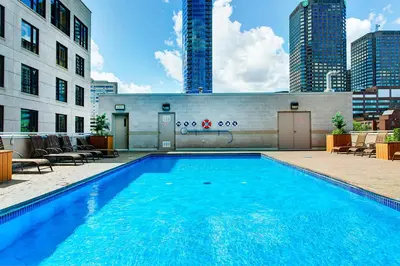 a large blue swimming pool in front of a building at Le Mille Neuf Apartments Modern Comfort in Downtown Montreal in Montréal