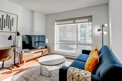 a living room with a blue couch and a tv at Le Mille Neuf Apartments Modern Comfort in Downtown Montreal in Montréal