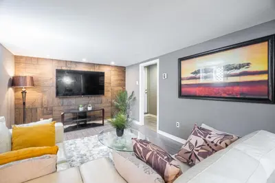 a living room with a white couch and a tv at Appart SS avec bain tourbillon CITQ 3I8I25 in Mascouche