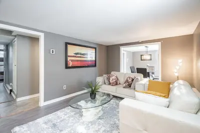a living room with a white couch and a table at Appart SS avec bain tourbillon CITQ 3I8I25 in Mascouche
