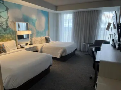a hotel room with two beds and a desk at Courtyard by Marriott Montreal Brossard in Brossard