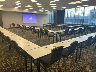 a conference room with tables and chairs and a screen at Courtyard by Marriott Montreal Brossard in Brossard