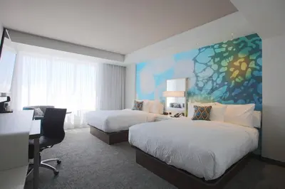 a hotel room with two beds and a desk at Courtyard by Marriott Montreal Brossard in Brossard