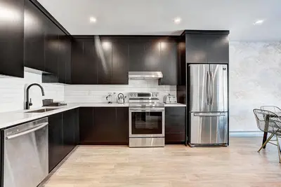 a kitchen with black cabinets and a stainless steel refrigerator at Burgundy Lofts - Marché Atwater in Montréal