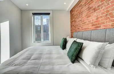 a bedroom with a large bed with a brick wall at Burgundy Lofts - Marché Atwater in Montréal