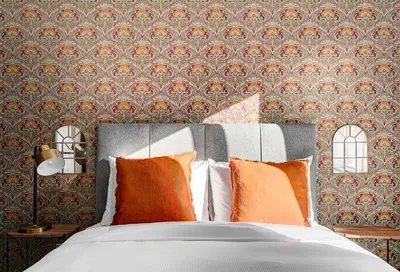 a bed with orange pillows in a bedroom with wallpaper at Burgundy Lofts - Marché Atwater in Montréal