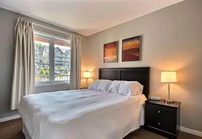 a bedroom with a large white bed and a window at Bromont-Condo sur la montagne in Bromont