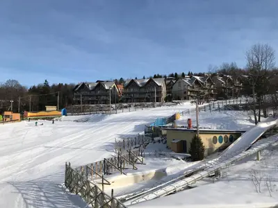 a snow covered ski slope with houses in the background at Bromont-Condo sur la montagne in Bromont