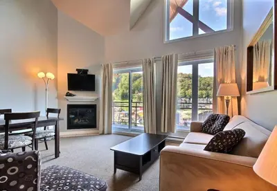 a living room with a couch and a dining room at Bromont-Condo sur la montagne in Bromont