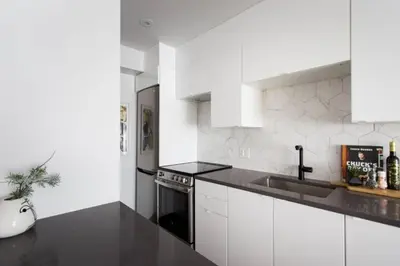 a white kitchen with a sink and a stove at Wonderful Studio in Little Italy with full bath by Den Stays in Montréal
