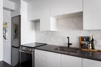 a white kitchen with a sink and a stove at Wonderful Studio in Little Italy with full bath by Den Stays in Montréal