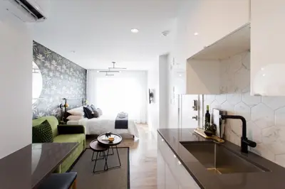 a kitchen with a sink and a living room with a bed at Sunny Green Palms Micro Studio with Yard View by Den Stays in Montréal