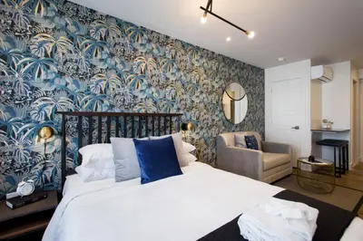 a bedroom with a bed with a blue and white wallpaper at Sunny Green Palms Micro Studio with Yard View by Den Stays in Montréal