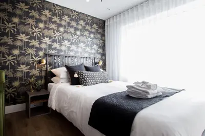 a bedroom with a bed with black and gold wallpaper at Sunny Green Palms Micro Studio with Yard View by Den Stays in Montréal