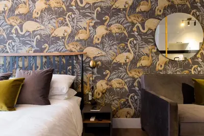a bedroom with a bed and a wall with bird wallpaper at Fun & Funky Little Italy Studio with Full Kitchen by Den Stays in Montréal
