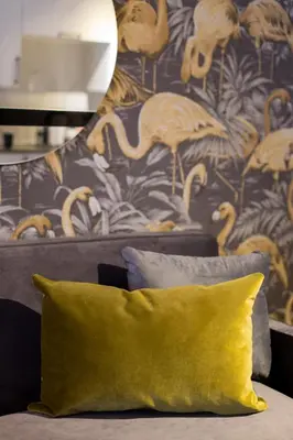 a couch with a yellow pillow and a wallpaper with flamingos at Fun & Funky Little Italy Studio with Full Kitchen by Den Stays in Montréal