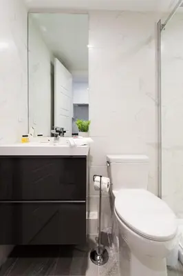 a white bathroom with a toilet and a sink at Serene and Styled Little Italy Studio full bath by Den Stays in Montréal