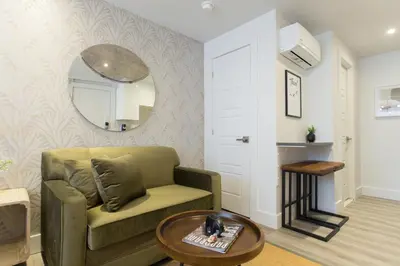 a living room with a green couch and a mirror at Serene and Styled Little Italy Studio full bath by Den Stays in Montréal