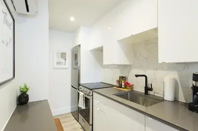 a kitchen with white cabinets and a sink at Serene and Styled Little Italy Studio full bath by Den Stays in Montréal
