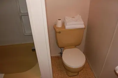 a bathroom with a toilet with towels on top of it at Motel Boisé in Blainville