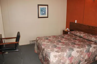 a bedroom with a bed and a table and a chair at Motel Boisé in Blainville