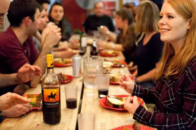 a group of people sitting at a table with a bottle of wine at Auberge du Plateau in Montréal