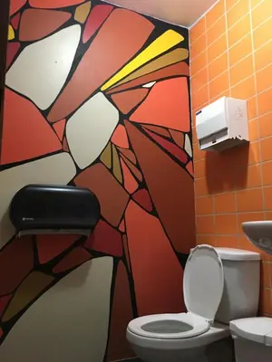 a bathroom with a painting on the wall next to a toilet at Auberge Alternative in Montréal