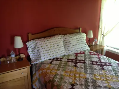 a bedroom with a bed with a quilt and two lamps at Gîte Au Blanc Marronnier in Racine