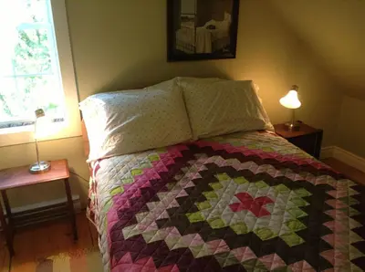 a bedroom with a bed with a quilt on it at Gîte Au Blanc Marronnier in Racine