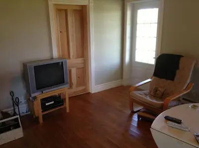a living room with a tv and a chair at Gîte Au Blanc Marronnier in Racine