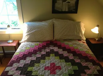 a bed with a quilt on it with two lamps at Gîte Au Blanc Marronnier in Racine